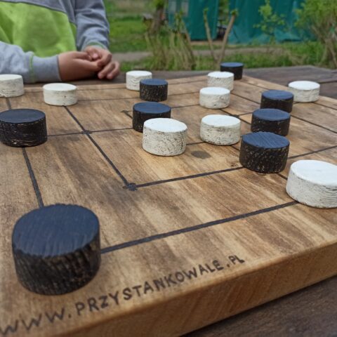 Zdjęcie młynka- gry planszowej wykonanej z drewna.