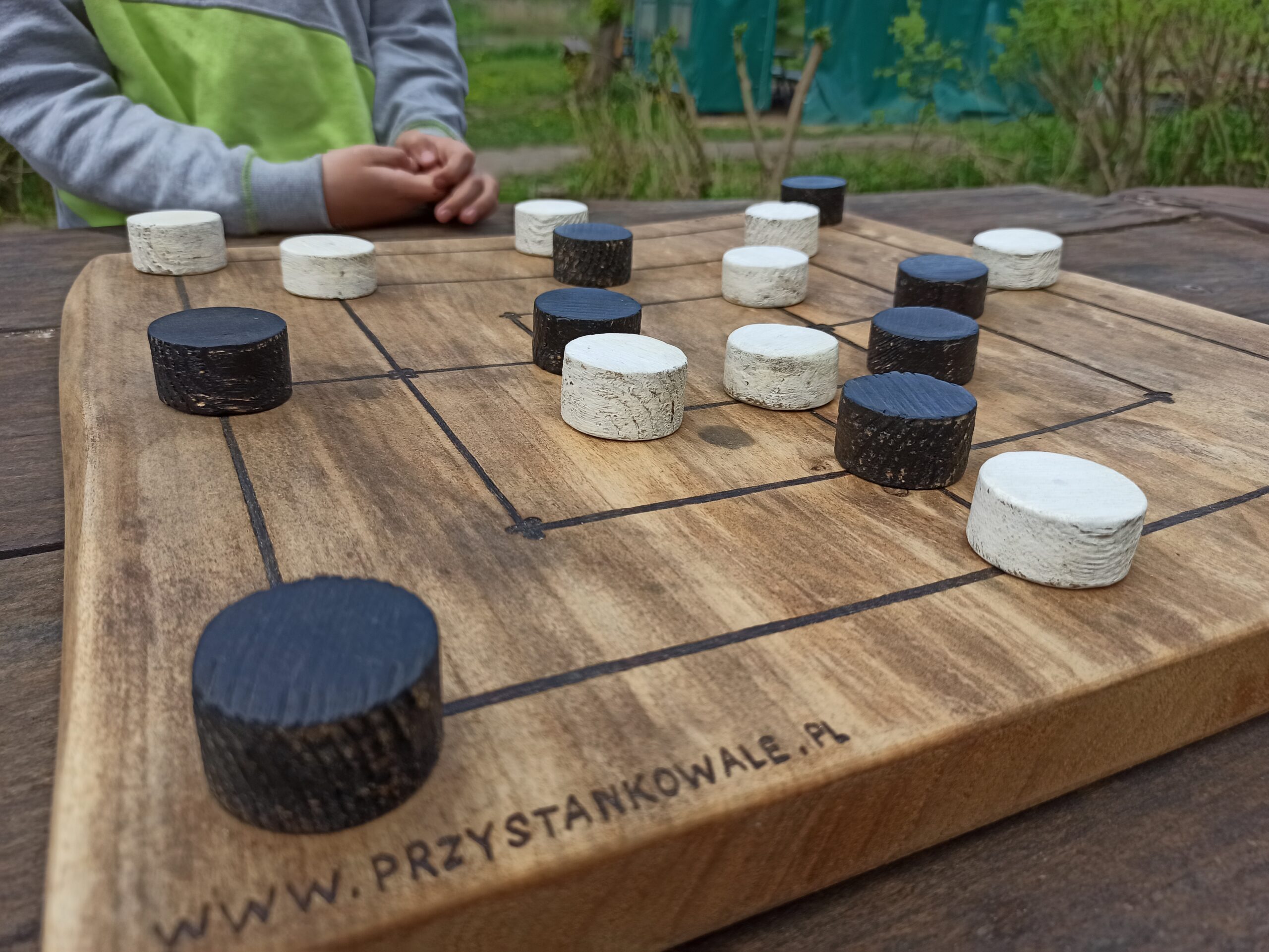 Zdjęcie młynka- gry planszowej wykonanej z drewna.